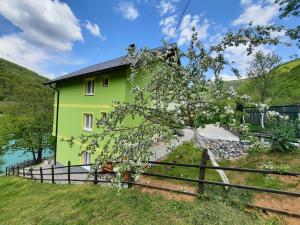 una casa amarilla y verde con una valla en Apartmani Vila na Drini, en Foča