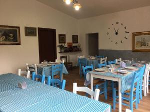 a restaurant with blue tables and chairs and a clock at AZIENDA AGRITURISTICA S'ARGALASI - B&B - AFFITTACAMERE Loc S'Argalasi Austis in Austis