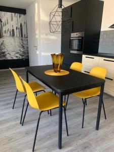 uma mesa preta com cadeiras amarelas numa cozinha em New Home Guest House em Gödöllő