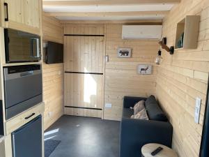 a living room with a couch in a tiny house at Au cœur de la ferme 2 in Lacroix-sur-Meuse