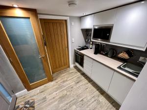 a kitchen with white cabinets and a wooden door at The Tower, 1 bed 1850's Tiny House in Maldon