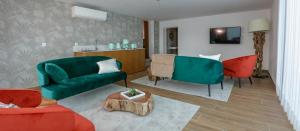 sala de estar con sofá verde y sillas rojas en Charme da Mourela, en Covelães