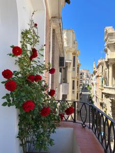 a balcony with red flowers on a building at Apartamentos Alfonso XIII in Córdoba