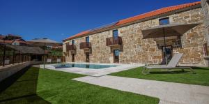 Una piscina con una silla y una sombrilla al lado de un edificio. en Charme da Mourela, en Covelães