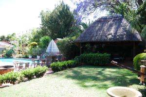 a small hut with a table and chairs next to a pool at Margaret's Place in Johannesburg