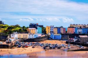 a group of boats on a sandy beach with buildings at The Potting Shed near Tenby, 100" Projector, Four poster bed, On-site HOT TUB access via Spa Pack in Tenby