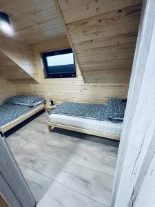 dwa łóżka w drewnianym domku z oknem w obiekcie Luksusowe Domki Kalimera w mieście Jantar