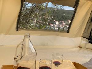 una botella y dos copas de vino en una mesa en Bigova Glamping, en Kotor