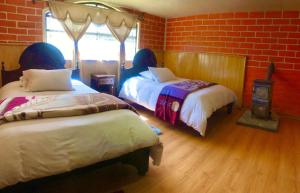 a bedroom with two beds and a brick wall at Hosteria Alpaka Quilotoa in Quilotoa