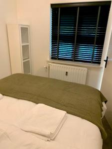 um quarto com uma cama com um cobertor verde e uma janela em Wilde Moeflon, geniet van de vrije natuur! em Otterlo
