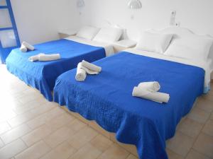 two beds with blue sheets and white pillows on them at The Three anchors Rooms Perissa in Perissa +57 photos