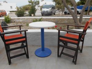 two chairs and a white table with a blue pole at The Three anchors Rooms Perissa in Perissa