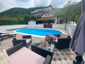 a swimming pool with chairs and a table and a house at Villa Enio in Bihać