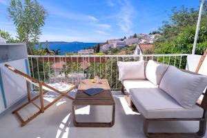 a patio with a couch and a table on a balcony at AWAKEN Gorgeous Sea View Apartment in Hvar