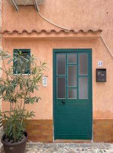 una porta verde e una pianta di fronte a un edificio di Casetta Milu’ a Ustica
