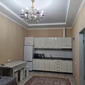 uma cozinha com armários brancos e um lustre em Иссык-Куль Кыргызстан, коттедж ЦО Палм Бич em Chok-Tal