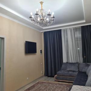 a living room with a couch and a chandelier at Иссык-Куль Кыргызстан, коттедж ЦО Палм Бич in Chok-Tal