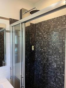 a bathroom with a shower with black tiles at Appartements St. Pancrace in Corte