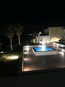 een nachtzicht op een zwembad met verlichting bij MARIA'S DREAM HOUSE in Eretria