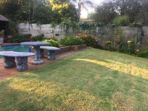 a backyard with two picnic tables and a pool at Rest Assured in Roodepoort