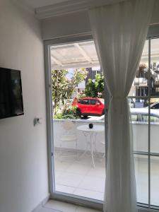 a sliding glass door to a patio with a table and a red car at White Suite Rooms in Kucukkoy