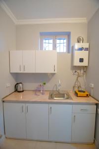 uma cozinha com armários brancos e um lavatório em Comfy corner em Telavi