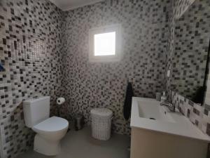 Un baño con inodoro, lavabo y ventana. en Casa Amarela de Santana, en Ribeira Grande