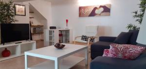 uma sala de estar com um sofá azul e uma televisão em Lovely new House - Guests Apartments em Olhão
