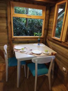 a table and chairs in a cabin with a window at La Cabaña de Huckleberry in El Retiro