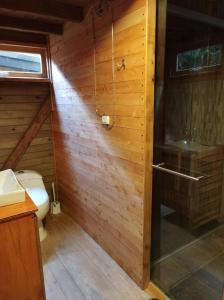 a bathroom with a toilet and a wooden wall at La Cabaña de Huckleberry in El Retiro