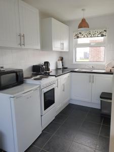 a white kitchen with white appliances and a window at Sands Holiday Chalet Dog friendly, free wifi, swimming pool and new gym passes and free club entry in Scratby