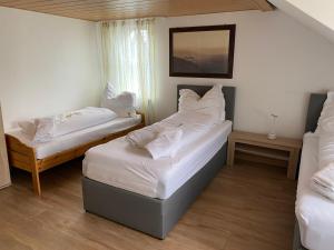 two beds in a room with white sheets and pillows at Dorfschenke in Siegen