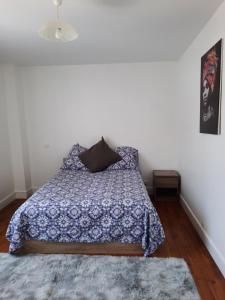 1 dormitorio con cama con colcha azul y alfombra en Maison Cosy en Ligugé