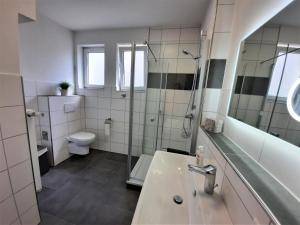 a bathroom with a sink and a shower and a toilet at FeelHome Ferienwohnung Tuttlingen in Tuttlingen