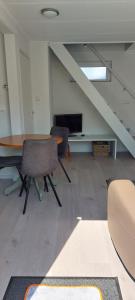 een kamer met een tafel, stoelen en een trap bij Wijngaardstraat 7a Domburg in Domburg