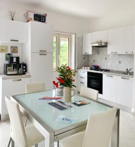 eine Küche mit Glastisch und weißen Schränken in der Unterkunft Anna's HOUSE Solarium Terrace in Pizzo