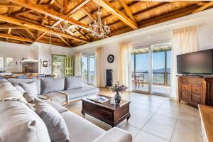 a living room with a couch and a tv at Aegean View Villa in Skopelos Town