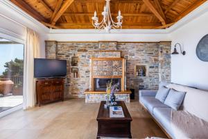 a living room with a stone wall at Aegean View Villa - Sea View Family Sanctuary in Skopelos Town