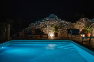 een zwembad voor een stenen muur 's nachts bij Villa Mista in Sutivan