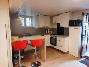 a kitchen with white cabinets and red bar stools at Maison Cosy in Ligugé