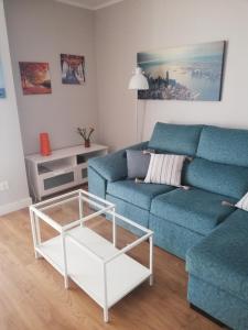 a living room with a blue couch and a coffee table at Apartamento Teatinos Málaga in Málaga