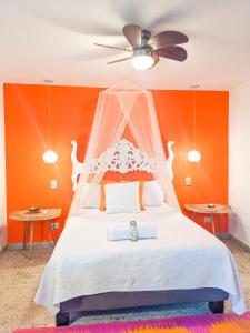 1 dormitorio con cama blanca y pared de color naranja en Magic Garden House en Cali