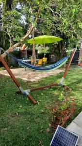 uma rede de descanso com um guarda-sol, uma mesa e cadeiras em villa do brazil em Ducos