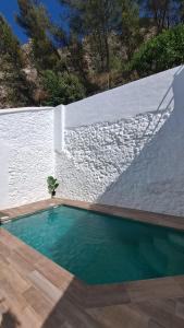 a swimming pool in front of a white wall at Casa El Villa in Zahara de la Sierra