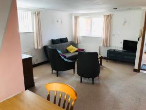 ein Wohnzimmer mit einem Sofa, Stühlen und einem Tisch in der Unterkunft Cosy house, 3 bedrooms, private parking, wifi, patio in Norwich