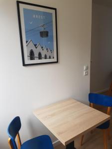 uma mesa de jantar com duas cadeiras azuis e uma foto em Brest : Beau T1 en centre ville em Brest