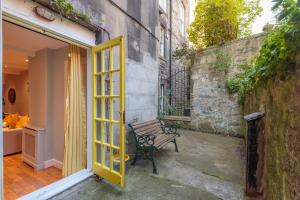 a yellow door open to a bench next to a building at Beautiful Hideout in Center of Edinburgh in Edinburgh