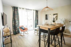 una sala da pranzo con tavolo, sedie e finestra di Bien chez soi à Evry appt 53m2 balcon parking a Évry-les-Châteaux