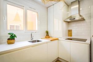 kuchnia z białymi szafkami, zlewem i oknem w obiekcie Tarifa Cozy House // PENTHOUSE - POOL - PARKING w mieście Tarifa