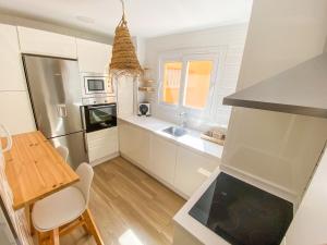 cocina con armarios blancos, mesa y comedor en Tarifa Cozy House // PENTHOUSE - POOL - PARKING, en Tarifa